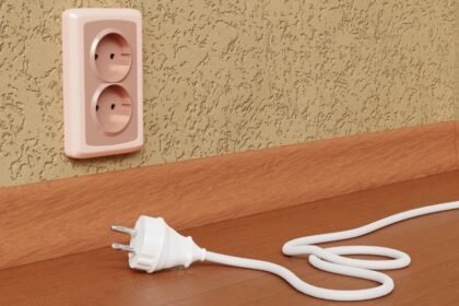 Egy konnektor és egy kihúzott elektromos csatlakozó a padlón, ami utazás előtt fontos lépés.