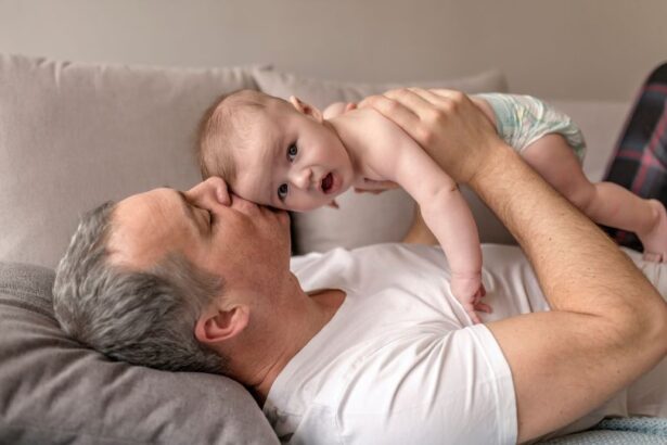 Egy apuka és kisbabája együtt pihennek a kanapén, a férfi szeretetteljesen csókolja a gyermeket.
