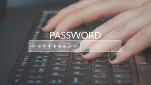 Egy kéz gépel egy jelszót egy laptop billentyűzetén, a képernyőn a 'PASSWORD' felirat látható.