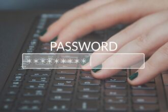 Egy kéz gépel egy jelszót egy laptop billentyűzetén, a képernyőn a'PASSWORD' felirat látható.