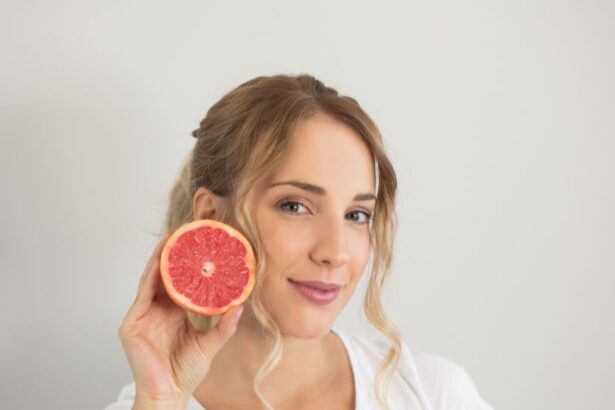 Egy fiatal nő mosolyogva tart a kezében egy fél grapefruitot, ami gazdag vitaminokban és antioxidánsokban, segítve az egészséges bőr fenntartását.