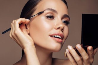 Egy fiatal nő sminket alkalmaz, miközben tükörbe néz, hangsúlyozva a szépségápolás fontosságát.