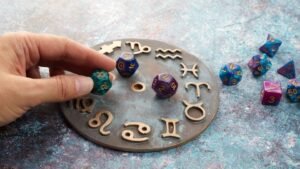 Egy kéz asztrológiai kockákat helyez el egy bronz szimbólumokkal díszített tárcsán, amely az aszcendens felfedezését szimbolizálja.