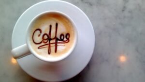 womensway 139 Egy csésze kávé, tetején a 'coffee' felirattal, fehér tányéron.