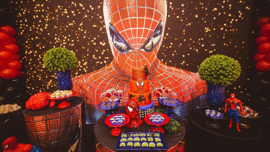 Egy Spider-Man témájú születésnapi buli dekorációja, ahol sütemények és figurák találhatók.