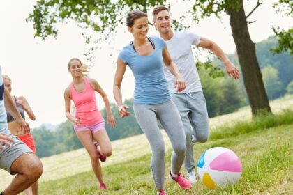 Fiatalok egy szabadban játszanak, boldogan futnak egy színes strandlabda körül.