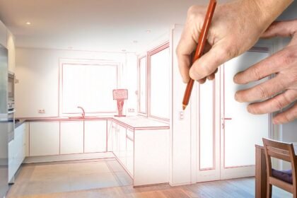 Egy modern konyha vázlata, ahol egy kéz ceruzával rajzolja a tervezett átalakítást.