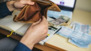 womensway 133 Egy üres pénztárca, amelyet egy férfi tart a kezében, körülötte számlák és készpénz.