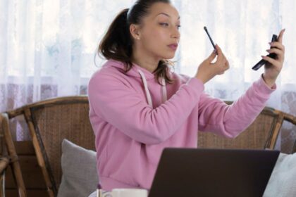 Egy fiatal nő sminket készít a tükör előtt, miközben otthon relaxál.