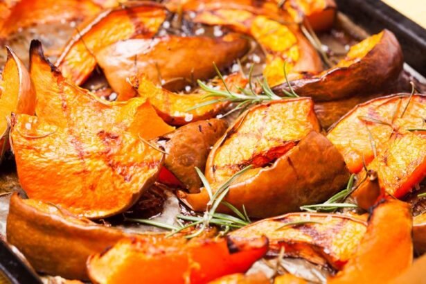 Sült tök szeletek rozmaringgal egy tepsiben, aranyló színben, ízletes és egészséges étel.