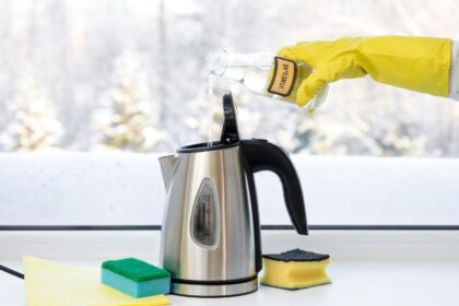 Egy vízforralóba ecetet önt egy sárga gumikesztyűs kéz, miközben a háttérben havas táj látható.