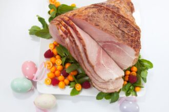 Főtt húsvéti sonka friss zöldségekkel és színes tojásokkal díszítve.