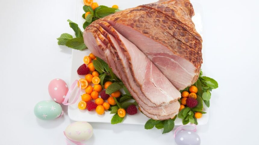 Főtt húsvéti sonka friss zöldségekkel és színes tojásokkal díszítve.