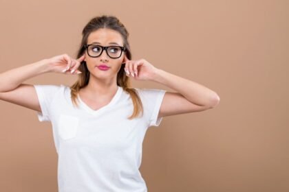 Egy fiatal nő, aki a fülét fogja, jelezve a füldugulás érzését nátha miatt.