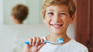 womensway 146 Egy mosolygó kisfiú fogkefével a kezében, készülődik a fogmosásra.