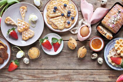 Húsvéti desszertek, köztük sütemények, gyümölcsök és csokoládé tojások egy ünnepi asztalon.