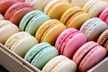 Színes macaronok egy dobozban, különböző ízekben és árnyalatokban, ideális kávé vagy tea mellé.