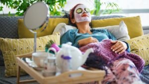 womensway 144 Egy nő relaxál a kanapén, uborkaszeletekkel a szemén, arcpakolással, miközben pihen és szépségápolást végez.