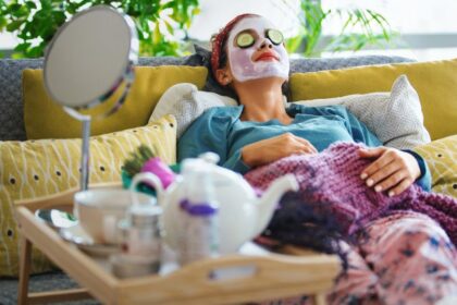Egy nő relaxál a kanapén, uborkaszeletekkel a szemén, arcpakolással, miközben pihen és szépségápolást végez.
