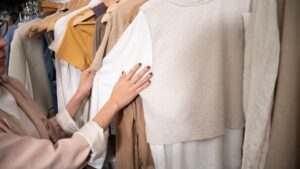 Egy nő válogat a ruhák között, időtálló alapdarabokat keresve a ruhatárához.