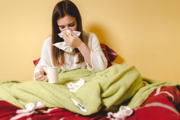 Egy fiatal nő takaróba burkolózva ül az ágyban, kezében bögrével, zsebkendőket használva.
