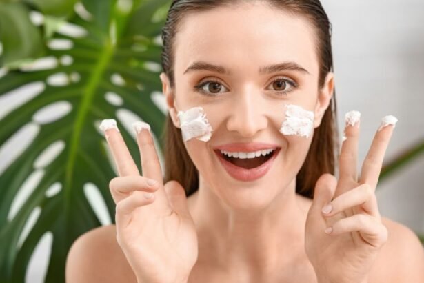 Egy fiatal nő arca krémmel van kenve, mosolyogva mutat a kamerába, háttérben zöld növényekkel.