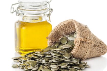 Egy üveg tökmagolaj és egy vászonzsák, amelyből tökmagok hullanak ki.