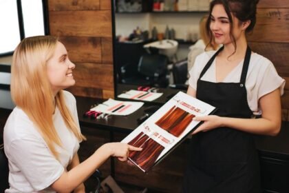 Egy fodrász bemutatja a hajszínmintákat egy fiatal nőnek a szalonban.