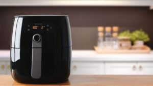 Egy modern, fekete Air Fryer konyhai pulton, digitális kijelzővel és gombokkal.