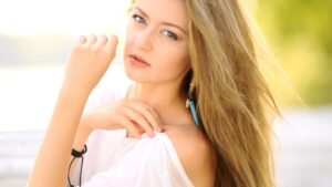 womensway 114 Egy fiatal nő természetes szépséggel és magabiztossággal néz a kamerába, haja lágyan fúj a szélben.