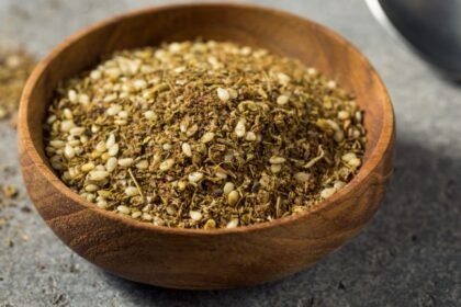 Egy fából készült tálban friss olasz fűszerkeverék látható, benne különböző fűszernövények és magvak.