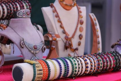 Különböző ásvány ékszerek, köztük nyakláncok és karkötők, egy piros terítőn kiállítva.