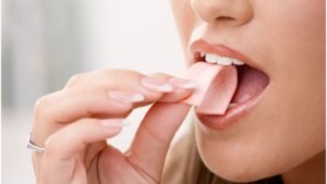 womensway 137 Egy nő rágógumit vesz a szájába, miközben mosolyog és figyelmesen néz.