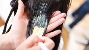 Egy hajfestés folyamatában a fodrász a festéket a hajra viszi fel, miközben a haj egészségét is figyelembe veszi.