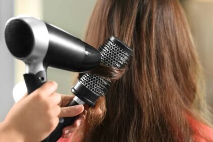 Egy hajszárító és kerek hajkefe használatával formázott haj, amely fényes és egészséges megjelenésű.