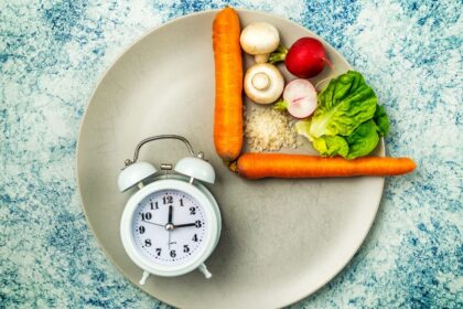 Egy tányéron zöldségek, rizs és egy óra, ami az időszakos böjtöt szimbolizálja.