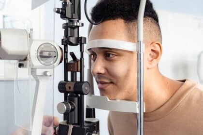 Egy fiatal férfi szemészeti vizsgálaton vesz részt, miközben a szemész egy modern eszközt használ.