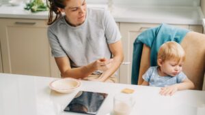 womensway 120 Egy édesanya próbálja etetni kisgyermekét, aki nem akar enni, az asztalon ételt és italt láthatunk.