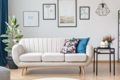 Modern, világos színű ülőgarnitúra, mellette zöld növény és dekoratív elemek a nappaliban.