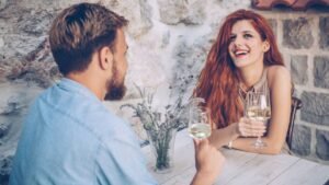 womensway 128 Egy fiatal pár vidáman beszélget egy étteremben, italokat tartanak a kezükben.