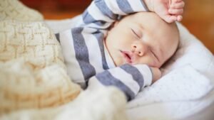 womensway 146 Egy kisbaba békésen alszik, csíkos ruhában, puha takaró alatt.