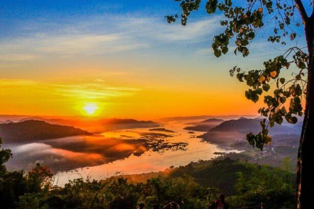 Naplemente egy gyönyörű tájon, ahol a folyó és a hegyek találkoznak, a természet nyugalmát sugallja.