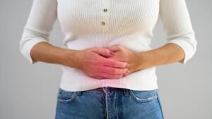 Egy nő, aki a hasát fogja, jelezve a zajos emésztés tüneteit.