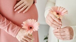 womensway 132 Két várandós nő, akik virágokat tartanak a kezükben, egyikük keze a hasán pihen.