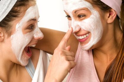 Két fiatal lány arcpakolást visel, vidáman nevetnek és játszanak egymással.