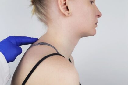 Egy nő profilból látható, amint orvosi vizsgálat során a háti gerincét ellenőrzik.