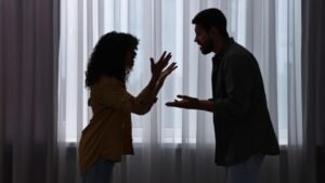 womensway 143 Egy pár vitázik, a nő gesztikulál, míg a férfi reagál, háttérben függöny.