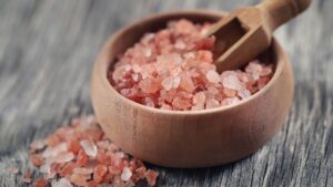 Rózsaszín só egy fából készült tálban, mellette egy kis kanál.