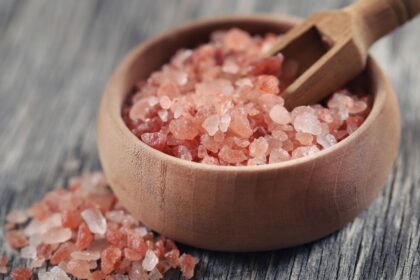 Rózsaszín só egy fából készült tálban, mellette egy kis kanál.