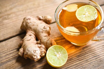 Friss gyömbértea citromszeletekkel, mellette friss gyömbérgyökér.